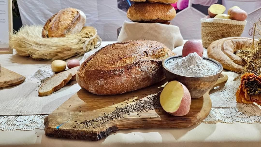 Aranjament rustic cu P&acirc;inea Anului 2025, cartofi, făină și chimen.